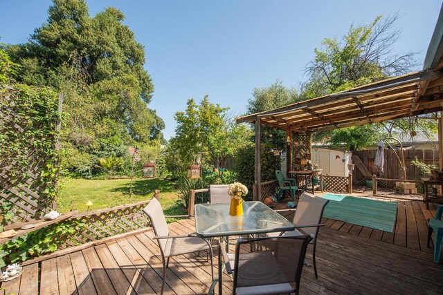 wooden deck with outdoor dining area, a yard, and a fenced backyard