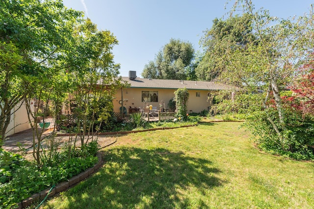 rear view of house with central air condition unit, a lawn, stucco siding, and a deck