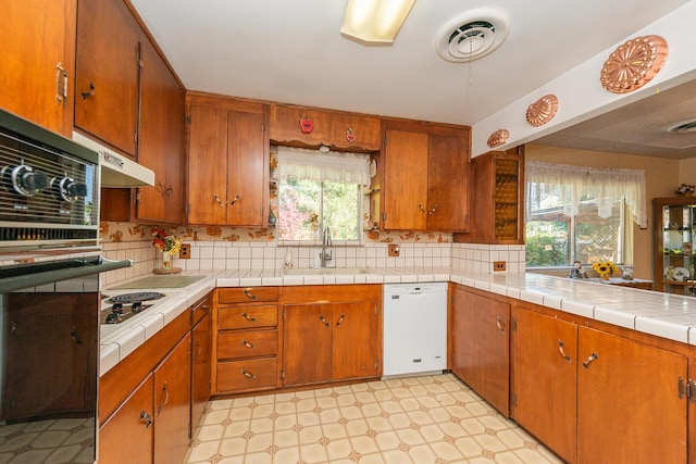 kitchen featuring brown cabinets, light floors, backsplash, a sink, and white appliances