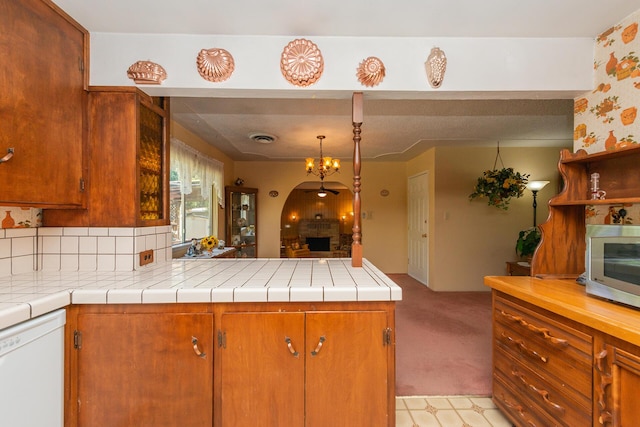 kitchen featuring a fireplace, light countertops, dishwasher, and brown cabinets