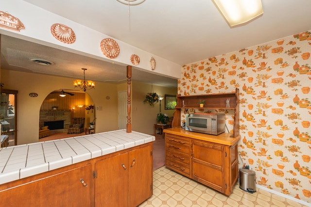kitchen with wallpapered walls, light floors, ceiling fan, stainless steel microwave, and visible vents