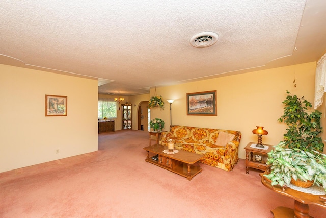 living area with arched walkways, carpet floors, a textured ceiling, and visible vents