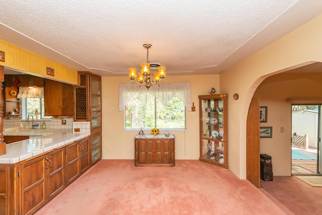 dining space with arched walkways, a textured ceiling, a wealth of natural light, and a notable chandelier