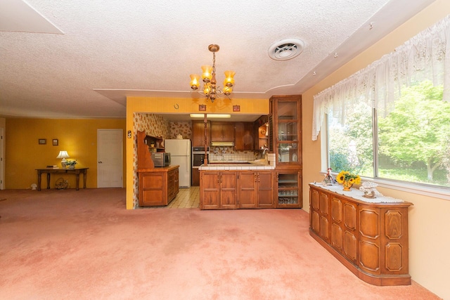 kitchen with brown cabinets, light carpet, light countertops, visible vents, and freestanding refrigerator