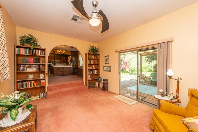 living area featuring ceiling fan, arched walkways, visible vents, and carpet