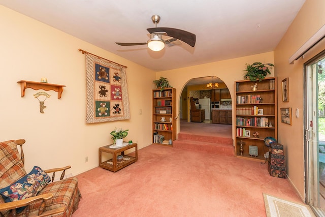 sitting room with arched walkways, visible vents, carpet flooring, and ceiling fan