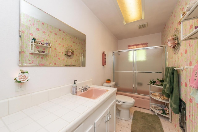 bathroom featuring combined bath / shower with glass door, vanity, toilet, tile patterned flooring, and visible vents