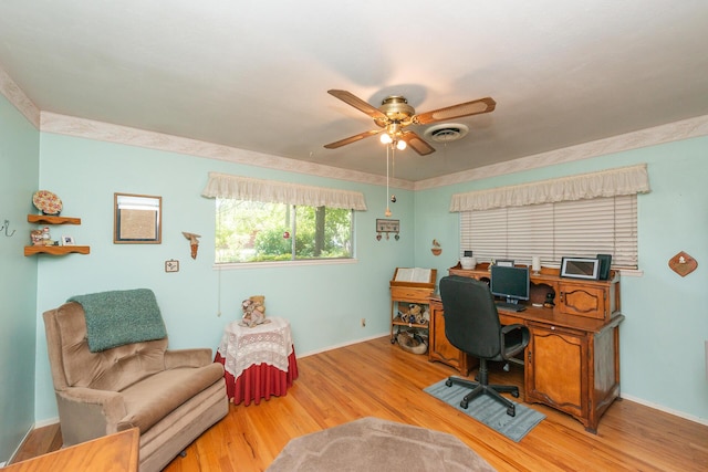 office space featuring baseboards, a ceiling fan, visible vents, and light wood-style flooring