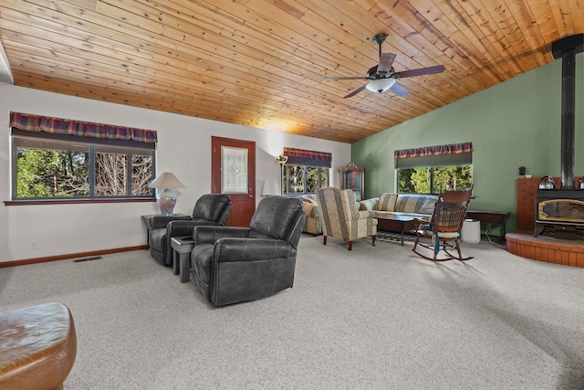 living area featuring vaulted ceiling, a wood stove, a ceiling fan, visible vents, and carpet floors