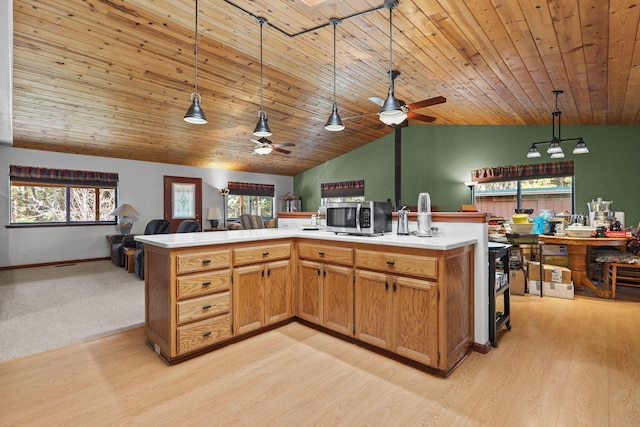 kitchen featuring vaulted ceiling, a ceiling fan, stainless steel microwave, hanging light fixtures, and open floor plan