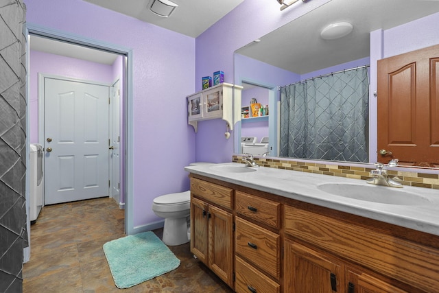 full bath featuring backsplash, toilet, separate washer and dryer, and a sink