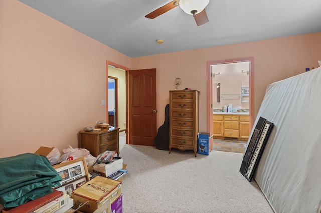 bedroom with light colored carpet, a ceiling fan, and ensuite bathroom