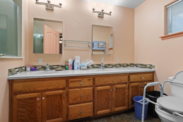 full bath featuring a sink, backsplash, double vanity, and toilet