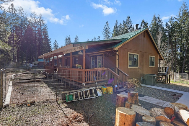 rear view of house with fence, central AC, and metal roof