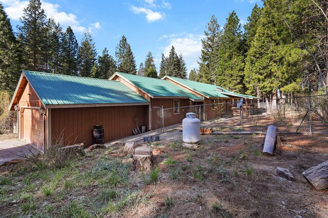 exterior space with fence, an outbuilding, a detached garage, and metal roof