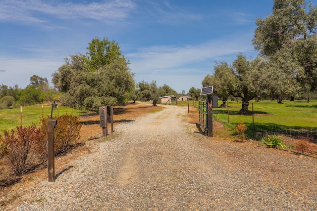 view of street featuring a gated entry, gravel driveway, and a rural view
