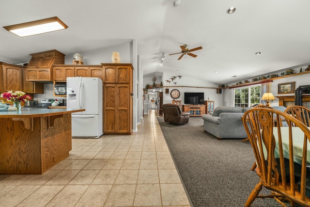 kitchen featuring vaulted ceiling, stainless steel electric range, white refrigerator with ice dispenser, and brown cabinetry