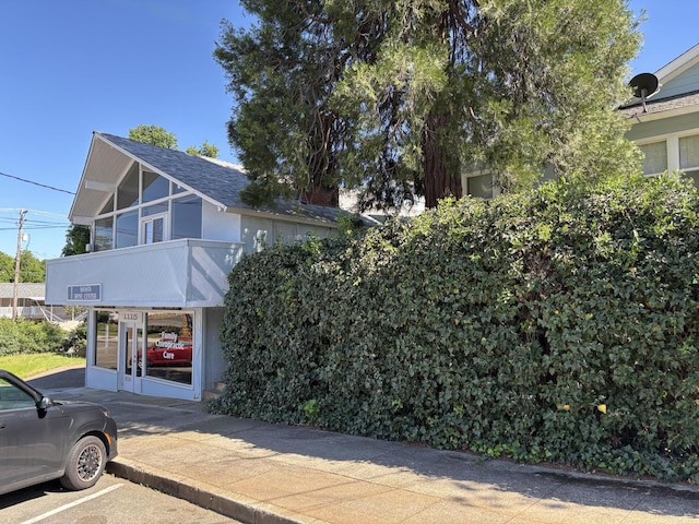 view of front facade with uncovered parking and roof with shingles