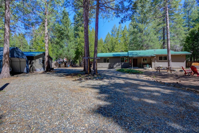 view of front of house featuring a storage shed, driveway, an outbuilding, and metal roof