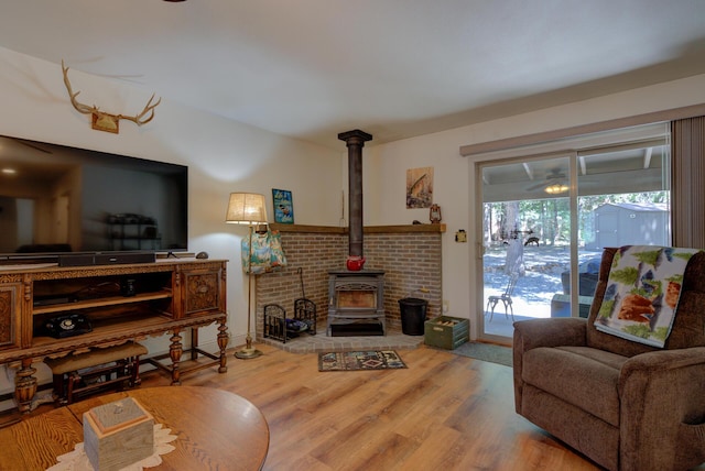 living area with wood finished floors, a wood stove, and baseboards