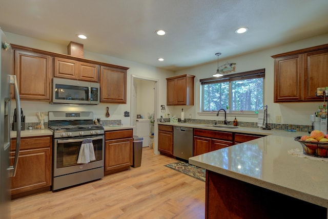 kitchen featuring recessed lighting, stainless steel appliances, light wood finished floors, and a sink