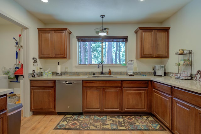 kitchen featuring light countertops, stainless steel dishwasher, brown cabinets, and a sink