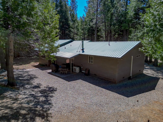 back of house featuring a patio area, crawl space, and metal roof