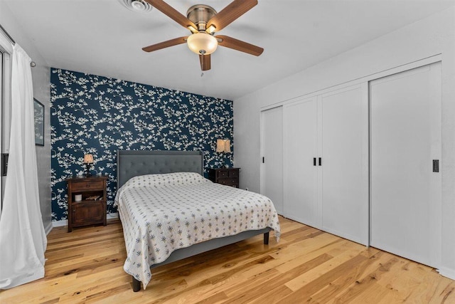7090 Rio Rancho Rd, Anderson, CA 96007 - bedroom featuring light wood finished floors, an accent wall, wallpapered walls, a ceiling fan, and a closet