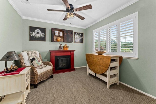 sitting room with ceiling fan, carpet floors, crown molding, and a glass covered fireplace