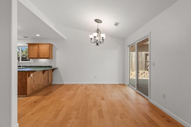 unfurnished dining area with light wood-style floors, visible vents, baseboards, and a notable chandelier