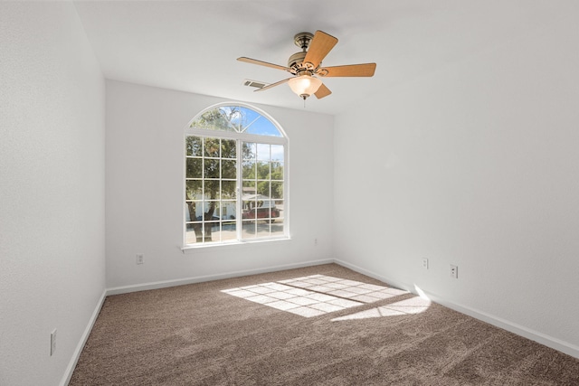 spare room featuring carpet, visible vents, baseboards, and ceiling fan