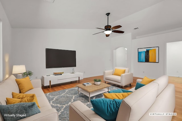 living area featuring arched walkways, visible vents, lofted ceiling, a ceiling fan, and wood finished floors