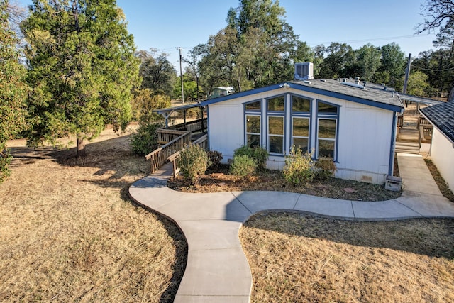 exterior space with central AC unit, crawl space, a shingled roof, and stairway