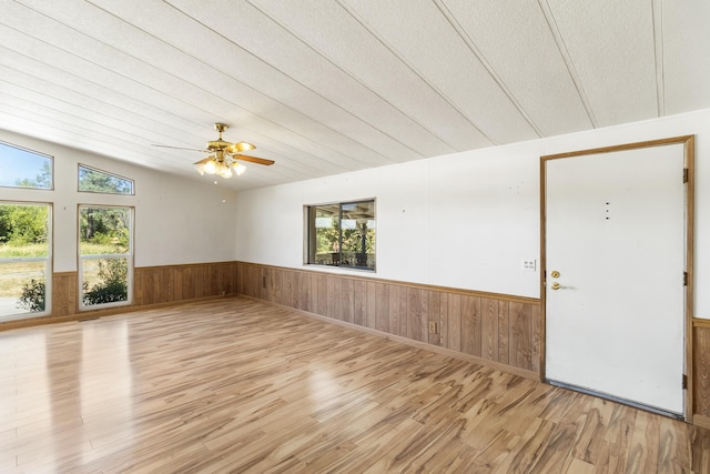 spare room featuring wainscoting, a wealth of natural light, wood walls, and wood finished floors