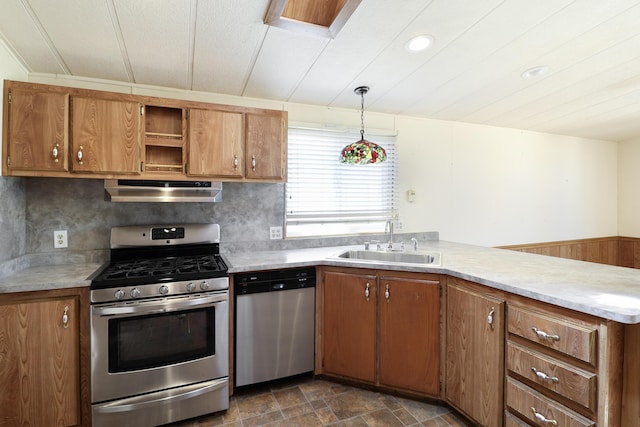kitchen with brown cabinets, appliances with stainless steel finishes, range hood, and a sink