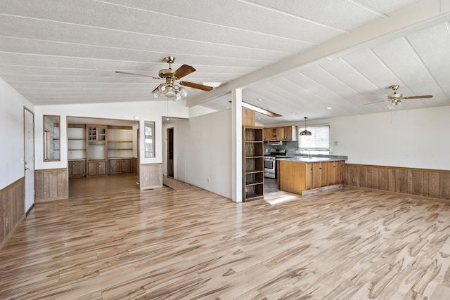 unfurnished living room featuring a wainscoted wall, lofted ceiling with beams, and ceiling fan