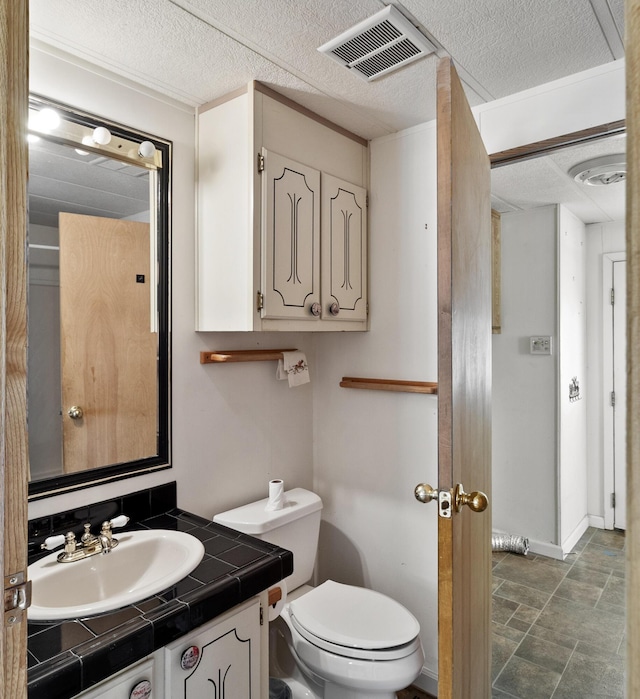 half bathroom with a textured ceiling, visible vents, toilet, and vanity
