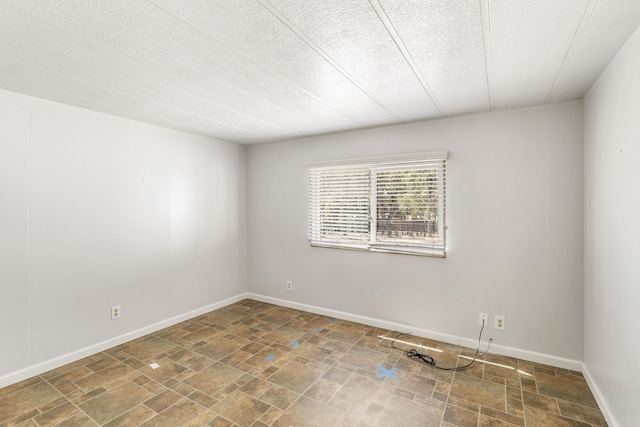 unfurnished room featuring baseboards, stone finish floor, and a textured ceiling