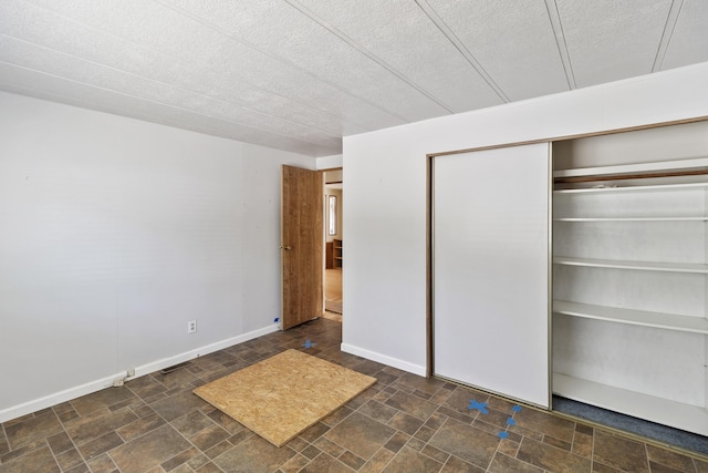 unfurnished bedroom featuring baseboards, a textured ceiling, and a closet