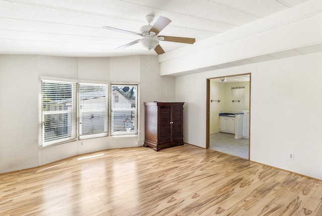 unfurnished bedroom featuring vaulted ceiling, wood finished floors, ensuite bathroom, and a ceiling fan