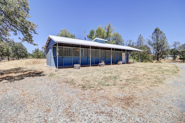 rear view of property with an exterior structure, an outdoor structure, and metal roof