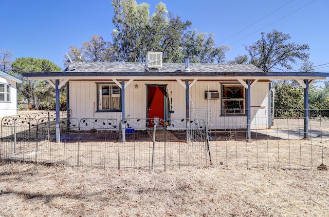 bungalow-style home featuring a fenced front yard, central air condition unit, a porch, a shingled roof, and a wall mounted AC