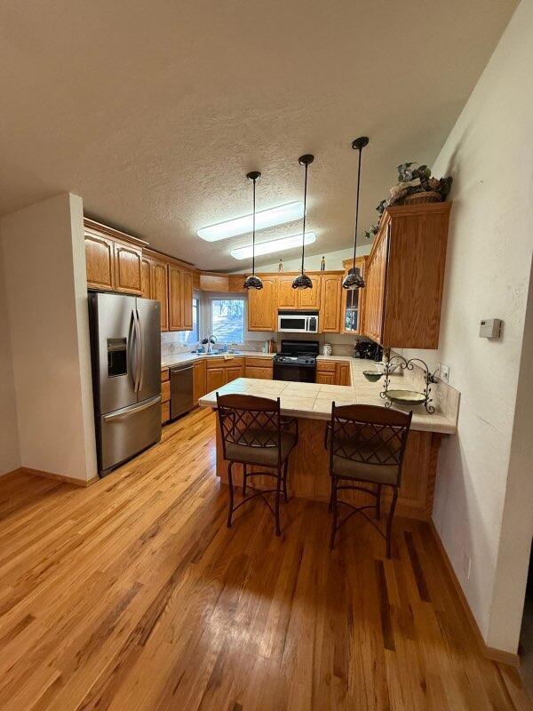 37150 Sapphire Rd, Burney, CA 96013 - kitchen featuring stainless steel fridge with ice dispenser, black range with gas cooktop, a peninsula, light wood-style flooring, and dishwasher