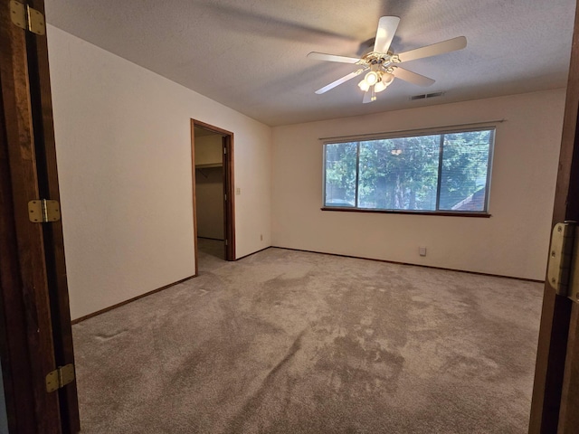 37150 Sapphire Rd, Burney, CA 96013 - unfurnished bedroom featuring light carpet, a textured ceiling, a ceiling fan, and a spacious closet