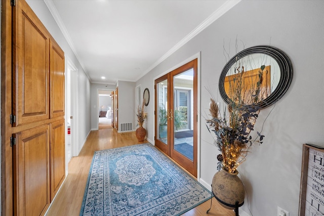 interior space with baseboards, crown molding, light wood-style floors, and visible vents