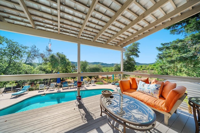 wooden deck with an outdoor pool, an outdoor living space, and a mountain view