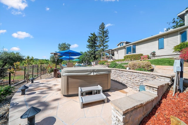 view of patio / terrace featuring a hot tub and fence