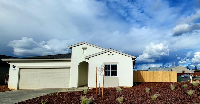 single story home featuring a garage, stucco siding, driveway, and fence