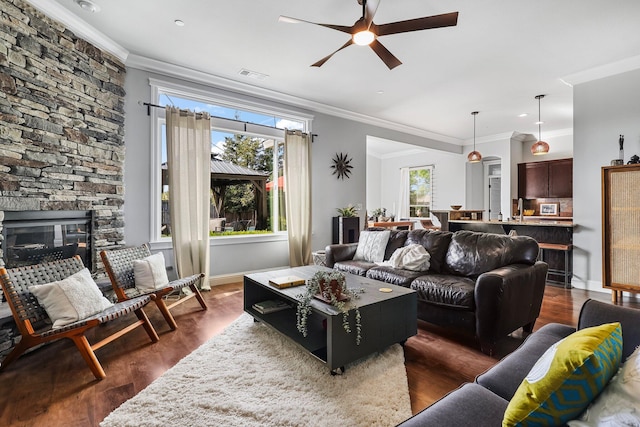 living area with crown molding, a ceiling fan, and dark wood-type flooring