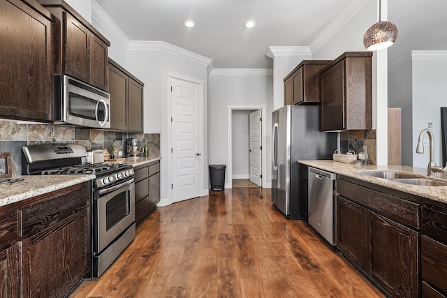 kitchen featuring a sink, appliances with stainless steel finishes, light stone counters, and dark brown cabinets